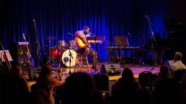 A man playing guitar at the Acorn Theater