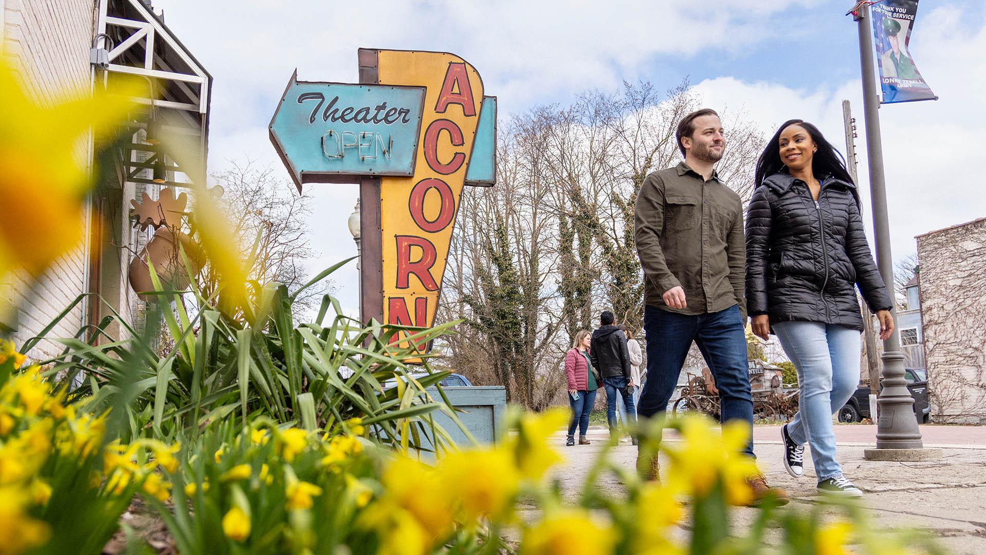 Two people walking next to The Acorn.