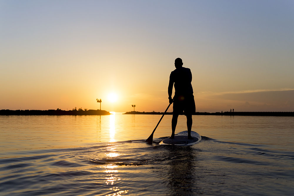 Man Paddleboarding Sunset Man paddleboarding towards the Lake Michigan sunset.