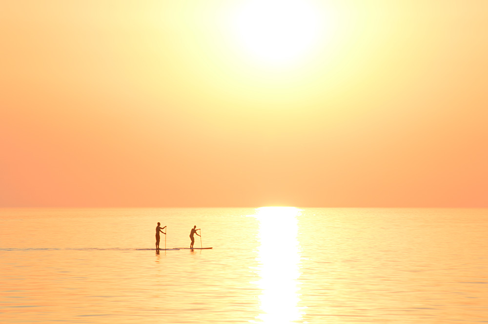 Two Paddleboarders Lake Michigan Two paddleboarders passing under the sunset on Lake Michigan.